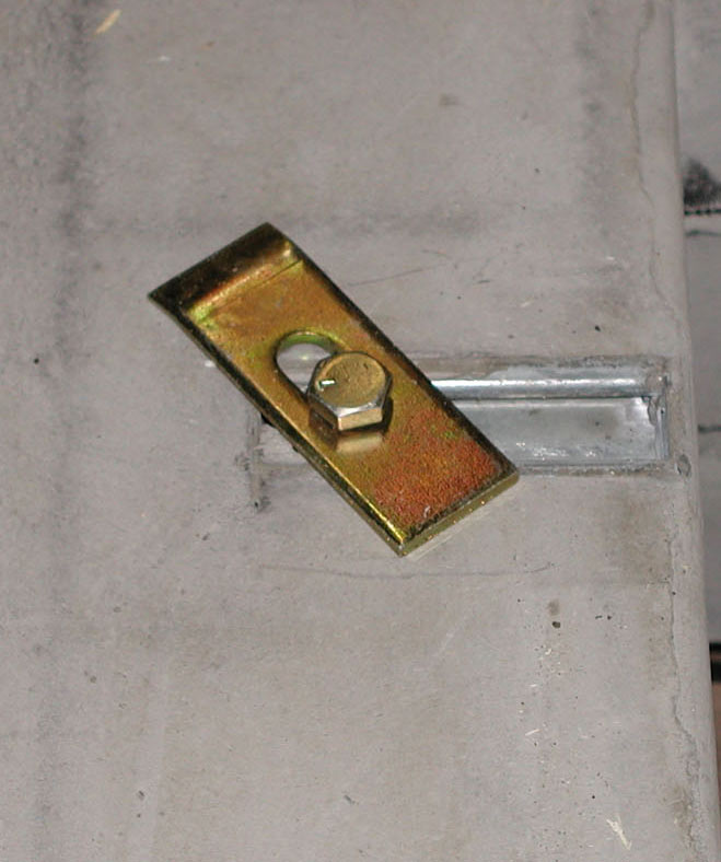 Photo of flat pad hardware - specifically a hold-down clamp installed into cast-in unistrut.